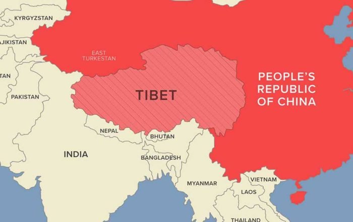 Map showing Tibet separately from the People's Republic of China, with surrounding countries including India, Bhutan, Nepal, and Myanmar. Tibet is shaded with red stripes, emphasizing its distinct identity from mainland China. India shares a border with Tibet